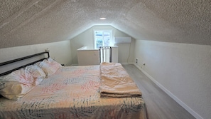 Un dormitorio abuhardillado pequeño con cama, escritorio y ventana.
