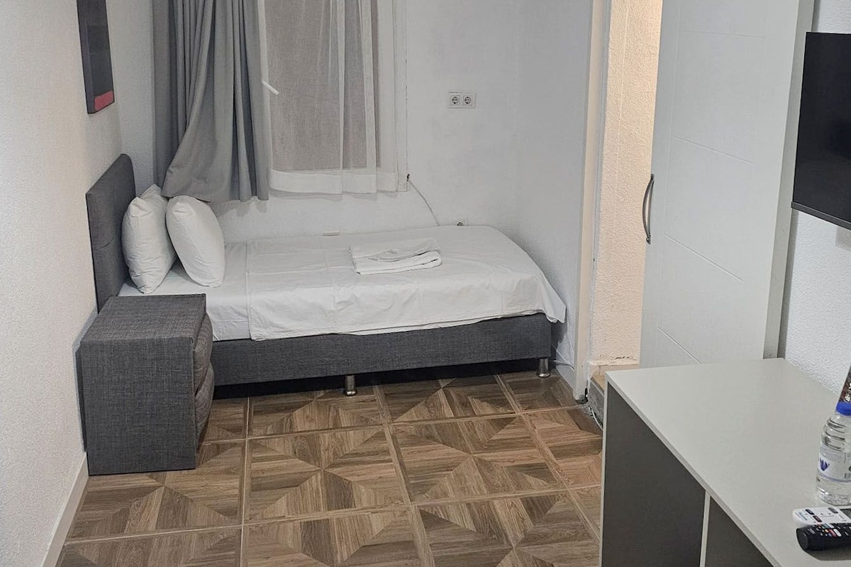Een kleine kamer met een bed, bureau en televisie.