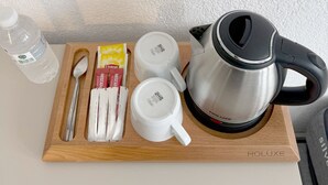 A wooden tray with a kettle, two white cups, a spoon, a water bottle, and some coffee packets. - Suda Pansiyon (Bodrum)