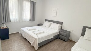 A modern hotel room with a bed, bedside tables, a bedside lamp, a window with curtains, and an air conditioning unit. - Suda Pansiyon (Bodrum)