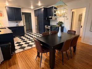 Une cuisine moderne avec des meubles de couleur sombre, un carrelage à motifs et un coin repas comprenant une table et des chaises.