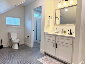 Une salle de bain équipée de toilettes, d’un lavabo, d’un miroir et d’un carrelage décoratif.