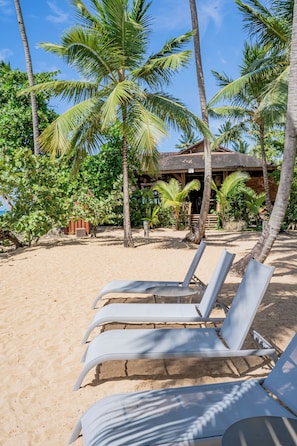 Ein Strand mit weißen Liegestühlen und Palmen.