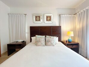 Ein Hotelzimmer mit einem großen Bett, zwei Nachttischen, einer Lampe und zwei gerahmten Bildern an der Wand.