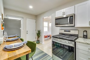 Una cocina moderna con armarios blancos, una estufa de acero inoxidable y un microondas.