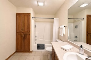 Une salle de bain avec un meuble en bois, une baignoire, une douche, des toilettes, un lavabo et un grand miroir.