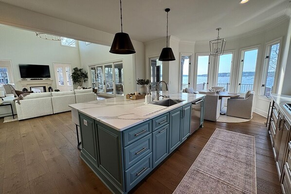 A spacious kitchen with a large island, modern pendant lights, and a view of the outdoors.