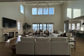 A spacious living room with a fireplace, a large TV, and a view of the outdoors.