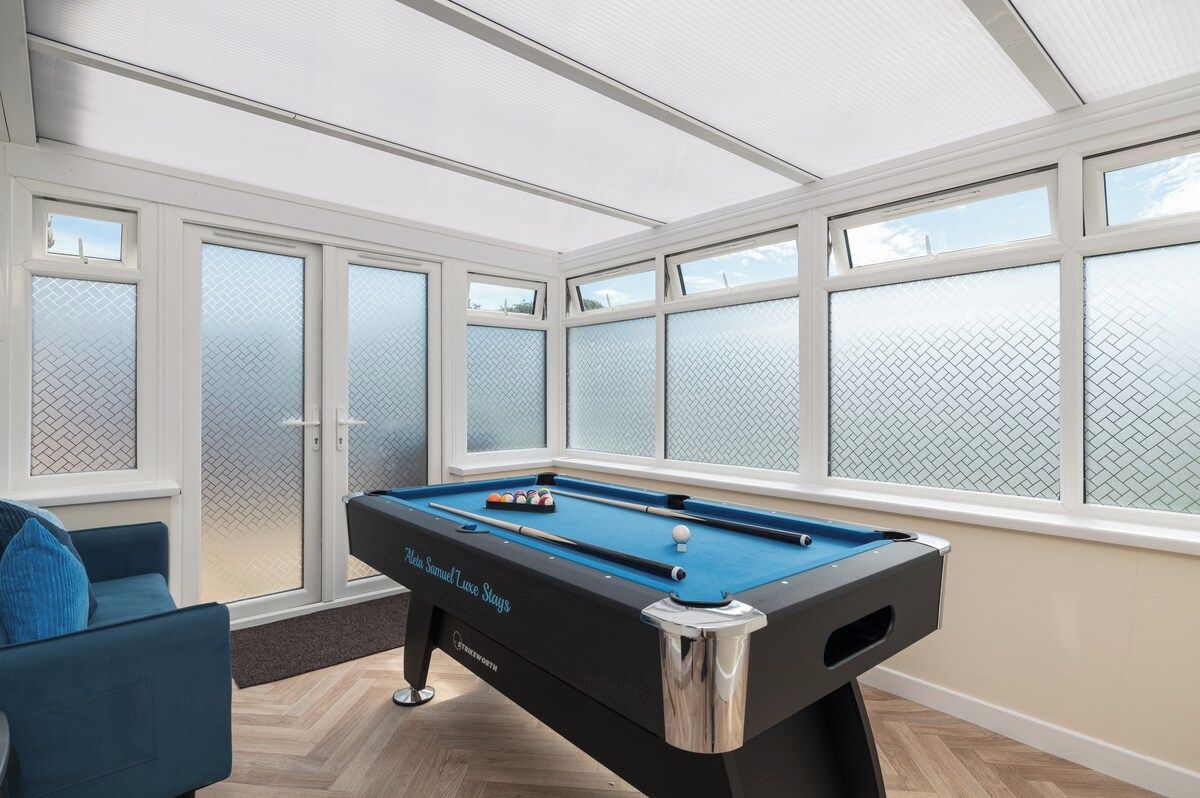 A pool table in a room with large windows and a view of the sky.