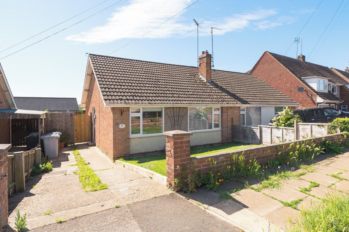 A residential property with a tiled roof, brick walls, a front garden, and a paved driveway.