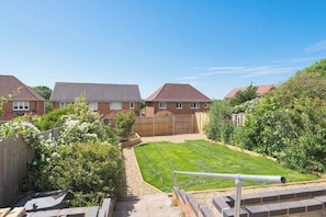 A residential backyard with a lawn, a wooden fence, and a brick wall. - Contractor Stay | Parking & Fast Wi-Fi | Sleeps 4 (Barton Seagrave)