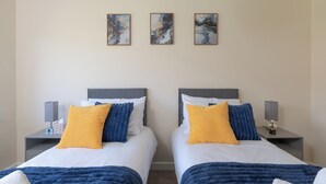 A double room with two beds, each with a headboard, bedside tables with lamps, and three abstract paintings on the wall. - Contractor Stay | Parking & Fast Wi-Fi | Sleeps 4 (Barton Seagrave)