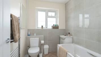 A compact bathroom with a toilet, bidet, and bathtub.