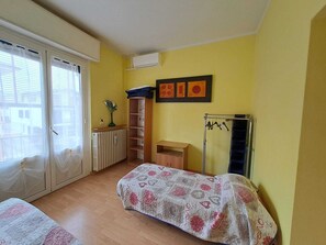 Quarto com cama, radiador, varal e janela com cortinas.