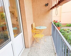 Ein Balkon mit Tisch und Stühlen, einem Blumentopf und Blick auf die Straße.
