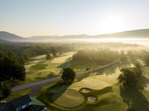 An aerial view of a golf course with multiple holes, pathways, and a distant mountain range. - Oversized Retreat | King Suite + Pool & Spa Access (Manchester)
