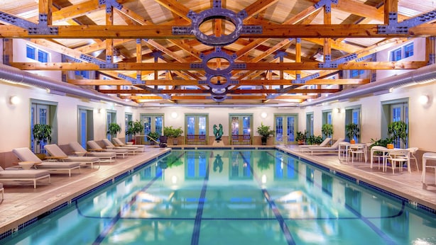 Una gran piscina interior con vigas de madera y una estructura decorativa central.