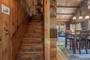 Eine Holztreppe mit gemustertem Teppich führt zu einem Essbereich mit Tisch und Stühlen.