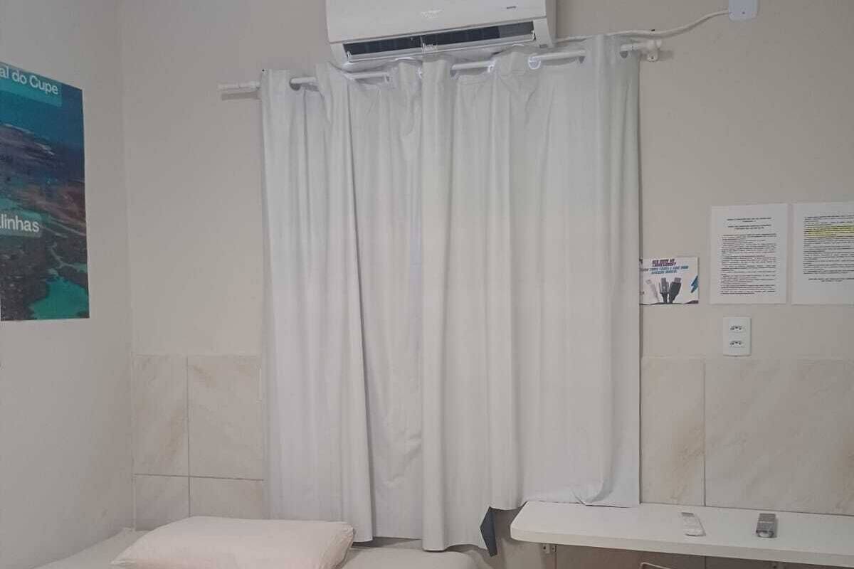 Un dormitorio con cama, aire acondicionado, escritorio y silla, y cortina.