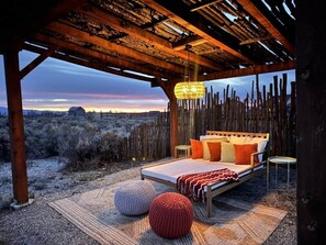 Ein Schlafzimmer mit Bett, Kissen, einer Hängelampe und Blick auf die Wüstenlandschaft.