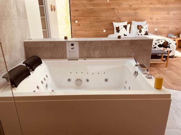 Ein modernes Badezimmer mit einer großen Badewanne, einer Holzwand und einem Bett mit einem Kissen mit Kuhmuster.