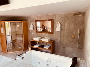 Un baño moderno con una bañera grande, cabina de ducha con paredes de vidrio y tocador de madera con espejo.