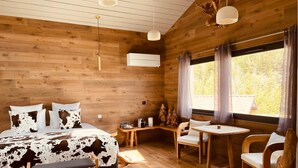 A wooden cabin-style room with a bed, a small table, two chairs, and a window with curtains. - Domaine Coul'Eau - Nordic Theme (Eaunes)