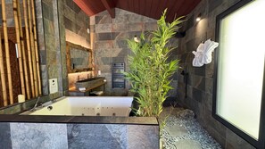 Une salle de bain moderne avec un lavabo en pierre, une grande baignoire et une plante en bambou.