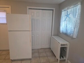 Eine kleine Küche mit einem weißen Kühlschrank, einem weißen Schrank und einer Tür.