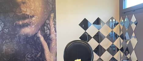 A dining area with a table, chairs, a candle, a pendant light, and a wall with a geometric pattern.
