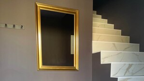 Een trap met witte marmeren treden, een paarse bank en een spiegel met gouden lijst aan de muur.
