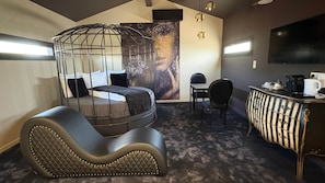Une pièce comprenant un lit, un bureau, une chaise, un téléviseur et une grande fenêtre.
