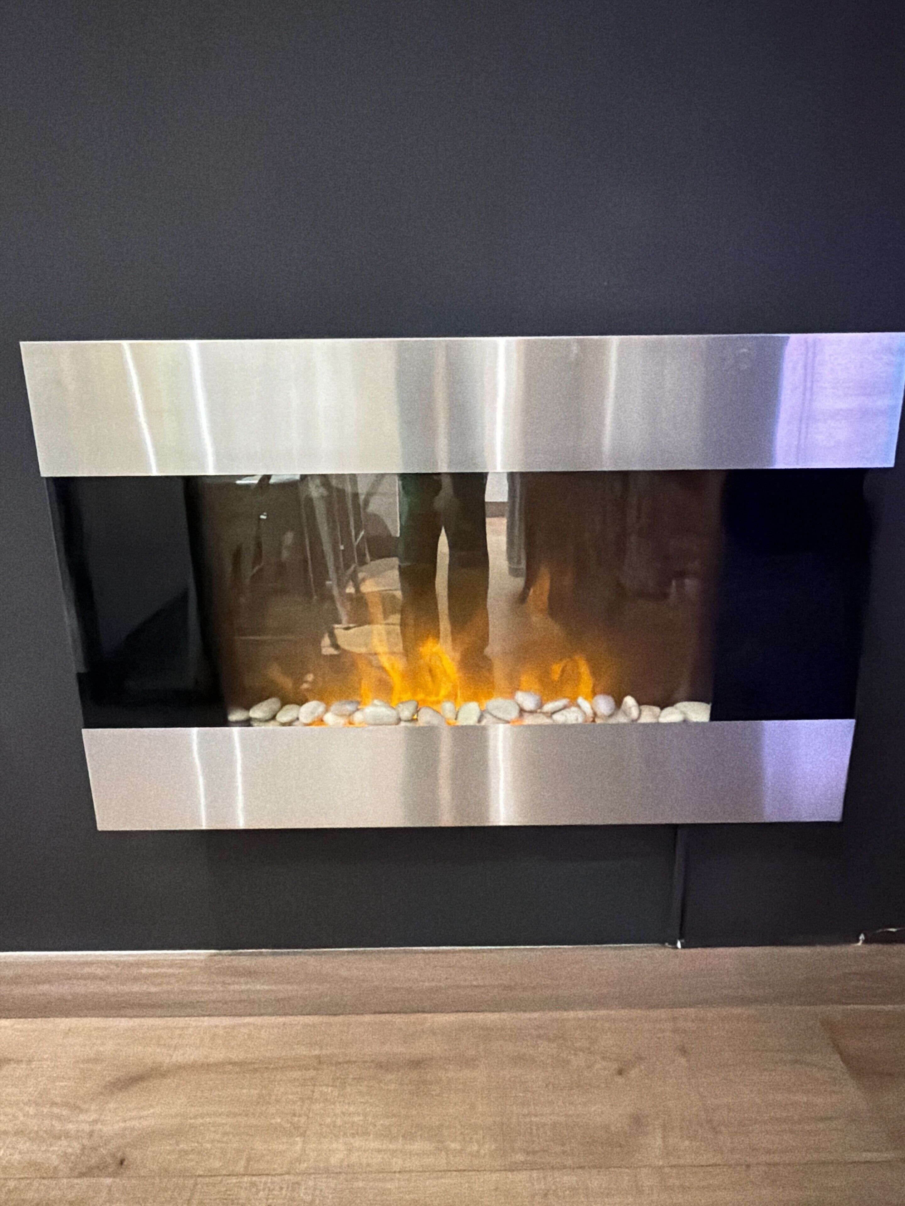 Ein moderner Kamin mit Metallrahmen, Steinunterbau und sichtbaren Flammen.