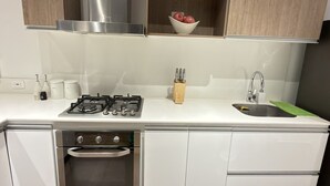 Una cuina moderna amb fogó de gas, forn, vàter i armaris de fusta.