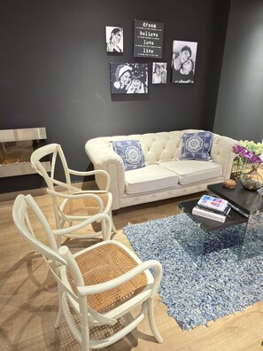 A living room with a white sofa, two white chairs, a blue patterned rug, and a coffee table with books. - Alcalá Park - Cedritos, Bogotá (Bogotá)