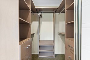 Um closet amplo com prateleiras abertas, cabideiro e porta deslizante.