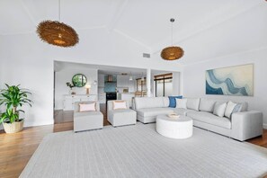 Ein modernes Wohnzimmer mit einem Ecksofa, einem runden Couchtisch und zwei Pendelleuchten.