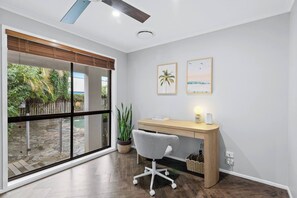Een moderne kantoorruimte met een bureau, stoel en grote ramen met uitzicht op een tuin.