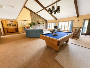 A spacious room with a pool table, a sofa, a fireplace, and a television.