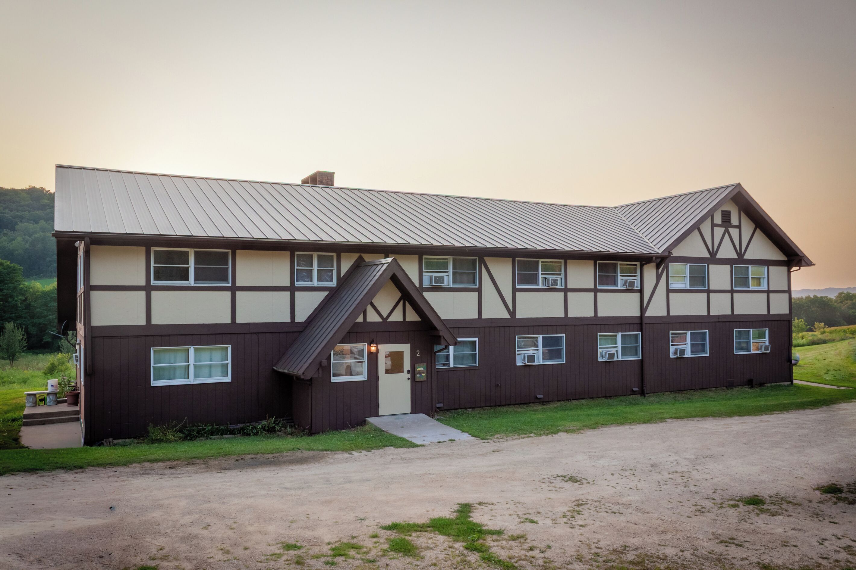 A two-story building with a sloped roof, multiple windows, and a small porch area.