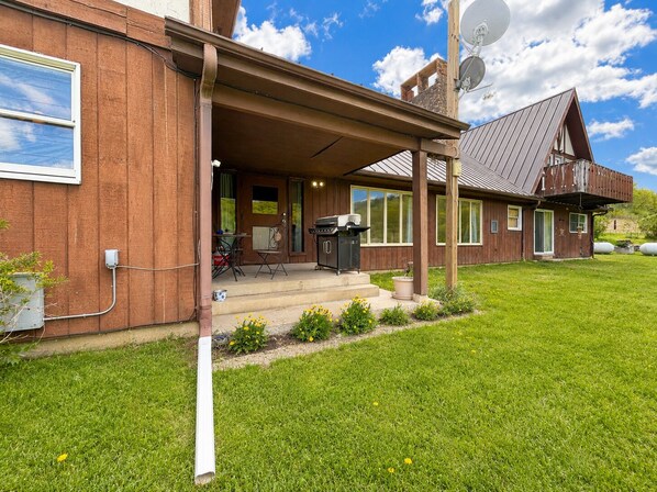 A wooden house with a covered porch, satellite dish, and outdoor seating area.