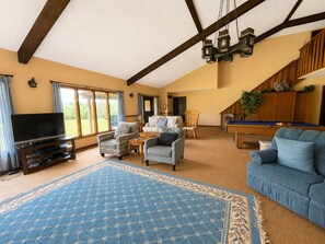 A spacious living room with a television, seating area, and a pool table.