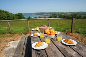 Ein Picknick mit Croissants, Orangen und Orangensaft auf einem Holztisch mit schöner Aussicht.