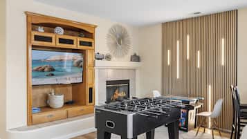 A living room with a television, fireplace, and foosball table.