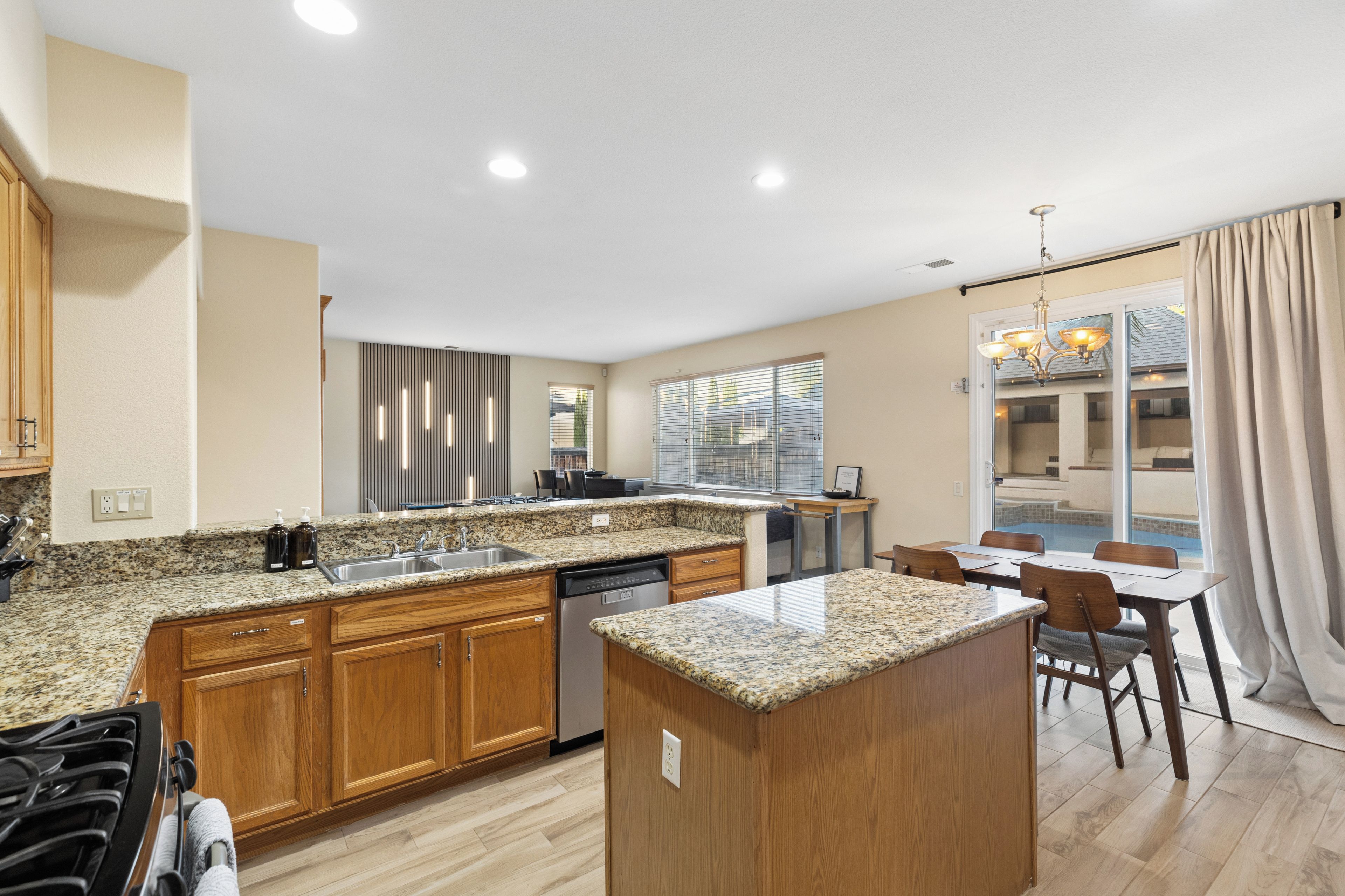 A modern kitchen with granite countertops, wooden cabinets, and a built-in dishwasher.