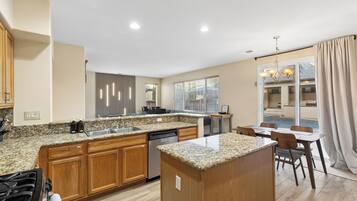 A modern kitchen with granite countertops, wooden cabinets, and a built-in dishwasher.