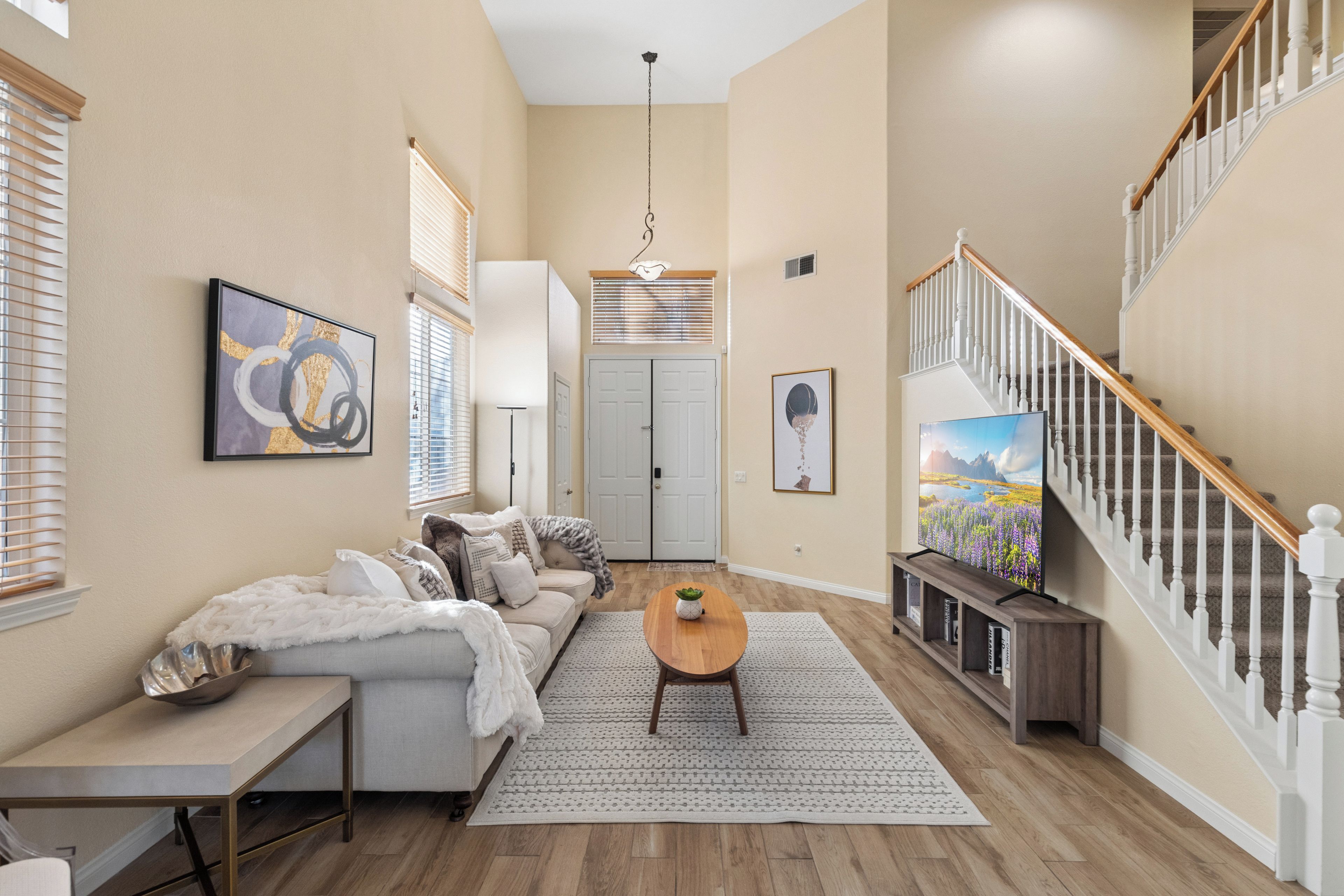 A spacious living room with a sofa, coffee table, and artwork on the walls.