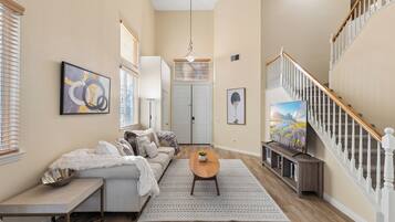 A spacious living room with a sofa, coffee table, and artwork on the walls.