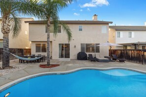 A residential property with a swimming pool, outdoor furniture, and palm trees.