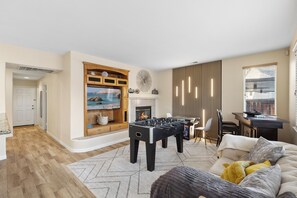 Una sala de estar con mesa de fútbol, chimenea, televisor y sofá.